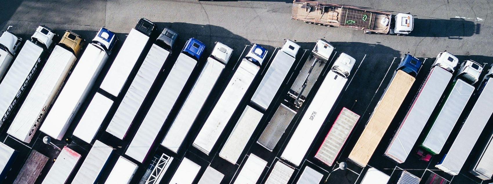 Vista aerea de un patio de maniobras lleno de tractomulas estacionadas en filas.